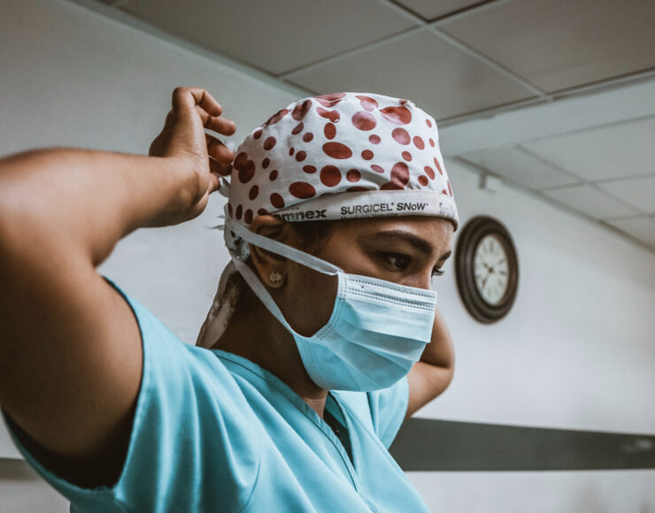 A nurse putting on a protective mask