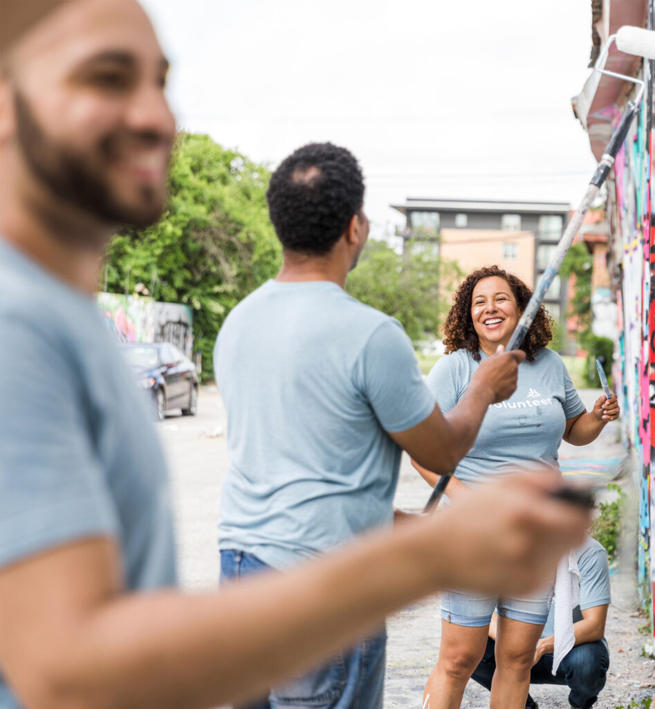 A woman and two male volunteers repainting a wall