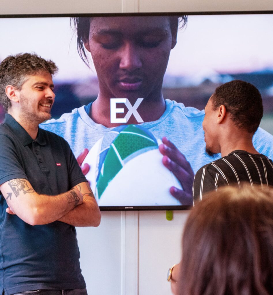 Blue Soft et vous - Carrièrepad. Twee Talents Bleus aan het praten. Een video van een vrouw die rugby speelt op de achtergrond.