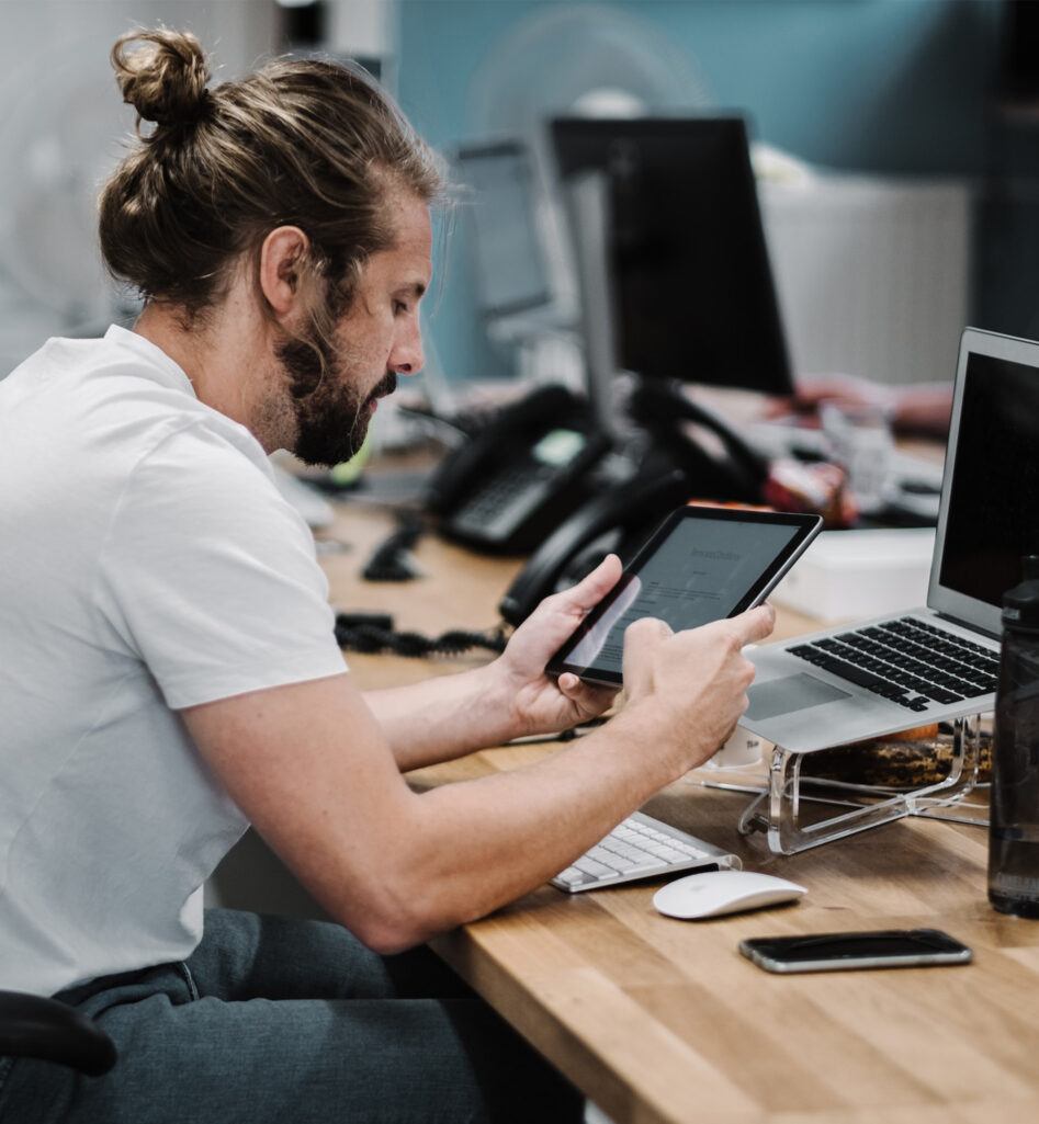 A man at his desk working on a tablet