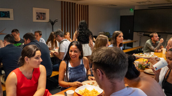 Teams zitten aan een tafel pizza te eten