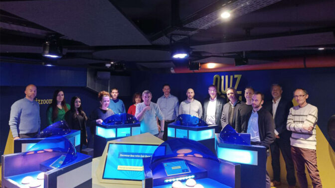 Group photo in front of quiz machines at an afterwork event