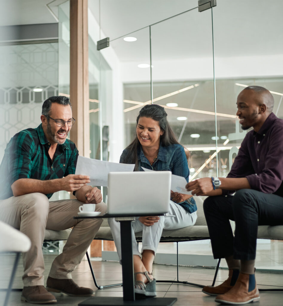 Three people around a table showing each other documents