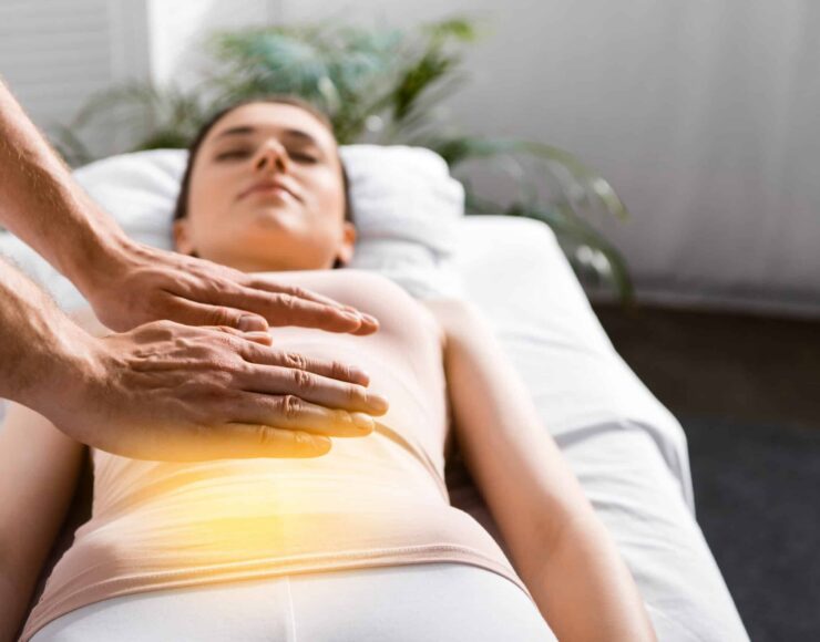 cropped view of healer standing near woman and holding hands above her stomach,