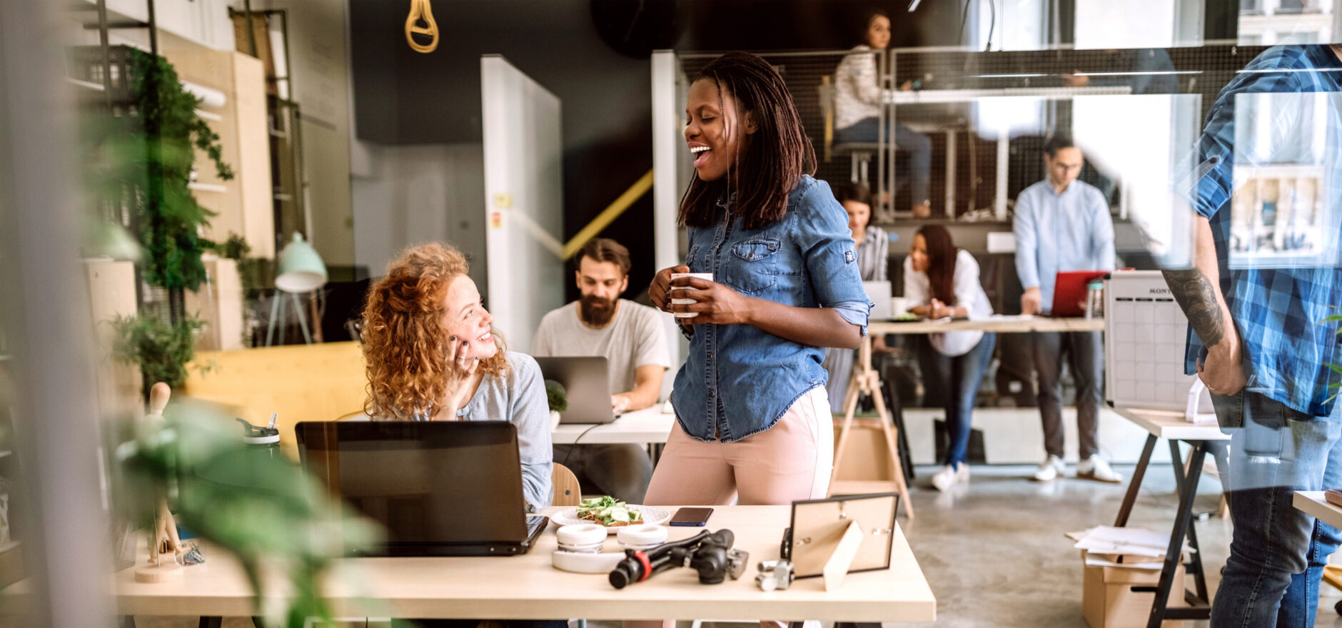 Two women chatting in front of a computer in the office