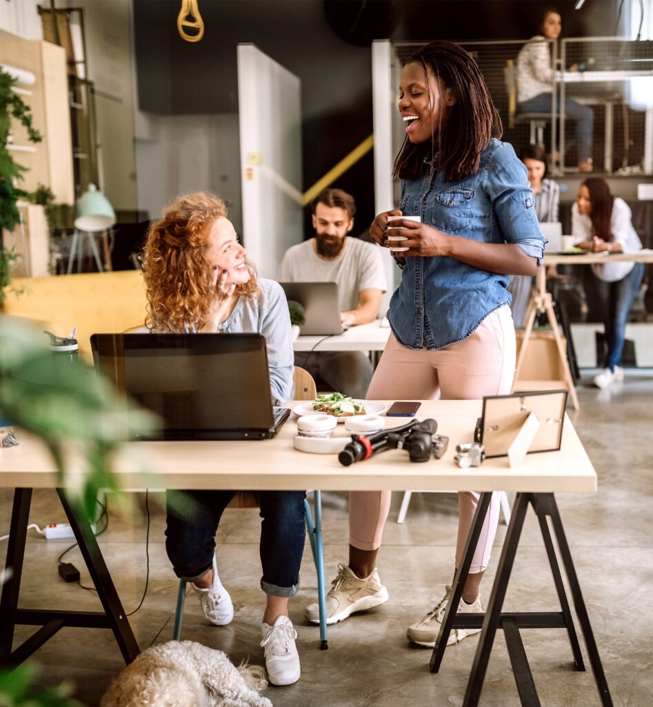 Two women chatting in front of a computer in the office